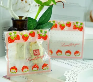 Cute strawberry cartoon self-adhesive candy packaging bag detail view, sweet gift pouch design.