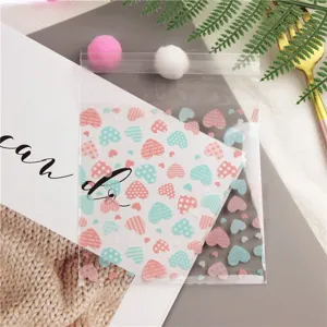 Sacchetti regalo adesivi trasparenti con motivi a cuore colorati per feste e dolci.