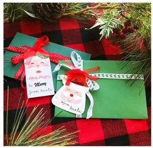 Detail view of Christmas Santa Claus paper hanging tags and green envelopes set with ribbons.