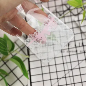 Primo piano di un sacchetto di plastica trasparente con pizzo bianco e fiocco rosa per dolci.