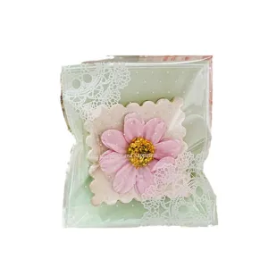 Mintgroene kanten cadeauzakje met roze bloemdecoratie voor snoepjes en kleine geschenken.