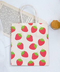Gros plan détaillé d'un joli sac cadeau en papier à motif de fraises avec poignée blanche.