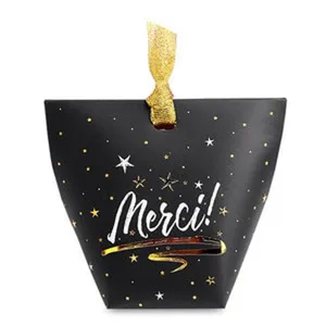 Detail view of the black pillow gift box featuring gold star patterns and a elegant ribbon.