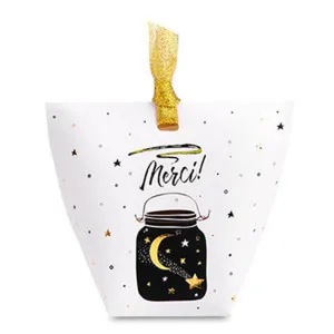 Detail view of a white paper pillow candy box with gold star print and ribbon close up.