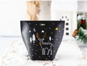 Detailed view of black Christmas candy paper box with gold deer pattern and snowy background.