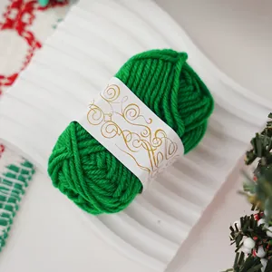 Close-up detail of green yarn ball with decorative gold pattern label on white tray.