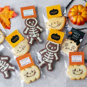 Ensemble de biscuits d'Halloween avec motifs de citrouille et squelette dans des sacs clairs.
