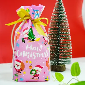 Sac cadeau de Noël rose avec nœud de ruban doré et motifs festifs de père Noël en détail