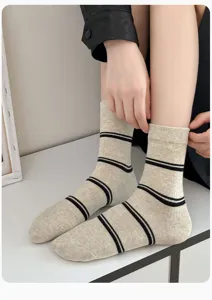 Close-up of women's autumn winter beige mid tube socks featuring classic black stripes.