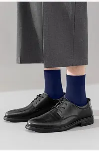 Detailed view of men's crew socks in deep blue, styled with classic leather shoes and trousers.