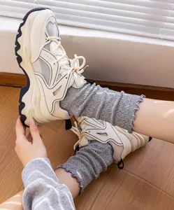 Detailed shot of women grey ruffle mesh mid-tube socks paired with chunky sneakers indoors.