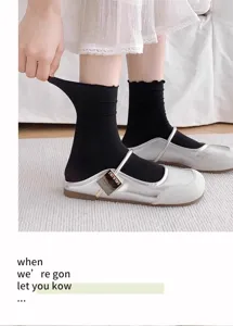Detailansicht schwarzer Eisseide-Socken mit Rüschenrand, kombiniert mit silbernen Schuhen.