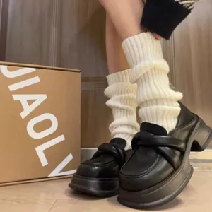 Gros plan détaillé de jambières en tricot blanc associées à des mocassins compensés noirs.