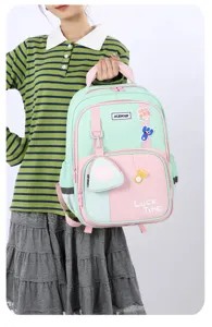 Detailed view of the mint green and pink student backpack featuring multiple compartments and cute badges.