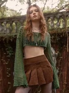 Detail view of green hollow-out crochet crop top with bell sleeves and brown skirt.