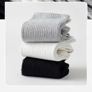 Solid color ribbed cotton socks detail shot showcasing stacked black, white and grey pairs.