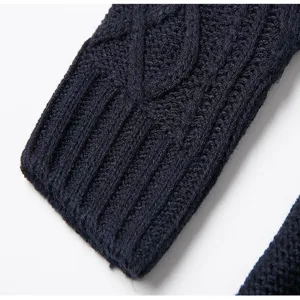 Close-up detail of dark blue women's knit sweater sleeve featuring classic cable knit texture.