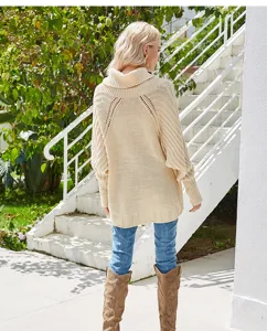 Detailed view of the back of a beige cable knit turtleneck sweater with batwing sleeves.