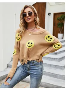 Dettaglio in primo piano di un maglione di maglia cammello strappato con smiley gialli.