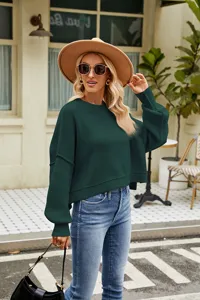 Close-up detail of the stylish dark green crewneck knit sweater with long sleeves and ribbed texture.