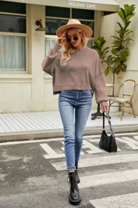 Detail shot of the loose cropped knit sweater worn by a model walking on a stylish street.