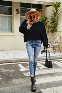 Detailed showcase of a stylish black long sleeve knit sweater in an outdoor setting.