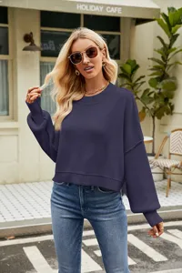 Detail shot of women's loose crop knit sweater long sleeve crew neck pullover in dark blue.