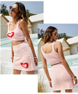 Close up detail view of pink fuzzy knit crop top and mini skirt set with red heart accent.