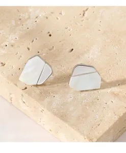 Gros plan de boucles d'oreilles en argent irrégulières uniques nacrées sur pierre.