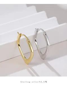 Gros plan détaillé des boucles d'oreilles créoles géométriques en argent sterling massif.