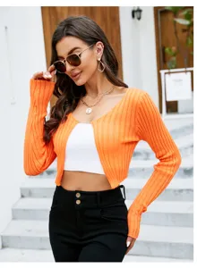 Detail view of the orange ribbed crop cardigan worn by model outdoors, stylish summer look.
