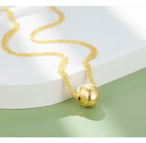 Close-up detail of a minimalist gold spherical pendant necklace with delicate multi-strand chains.
