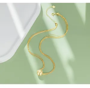 Elegant multi-strand gold necklace with spherical pendant, minimalist clavicle chain detail.