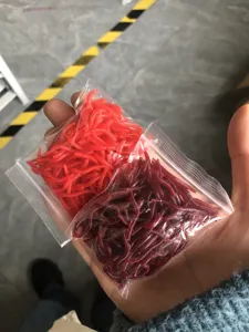 Close-up of soft fishing red worm lures in clear zipper bags, flexible and durable silicone bait.