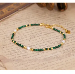 Detailed shot of vintage natural malachite and pearl beaded bracelet with gold accents.