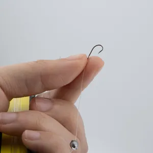 Outdoor fishing tackle detail view featuring sharp fish hook, transparent line and sinker setup.