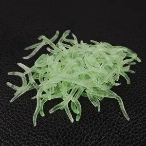 Closeup detail of luminous green soft fishing lures, earthworm and bloodworm simulation bait.