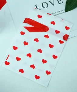 Gedetailleerd overzicht van matte plastic cadeautas met rode harten en rood lint trekkoord.