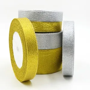 Close-up detail shot of shiny gold and silver glitter ribbon rolls for gift packaging.