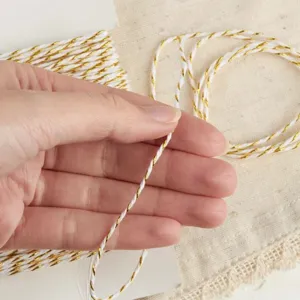 Fine white and gold metallic twisted cotton twine string for gift wrapping DIY crafts.