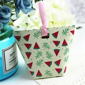 Detail van papieren snoepdoos met zomerse watermeloen print en roze lint voor het feest.