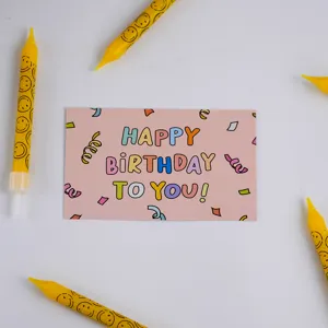Pink happy birthday greeting card detail shot with yellow smiley face candles for party.
