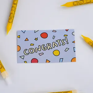 Detail view of a minimalist blue greeting card with colorful geometric shapes and text.