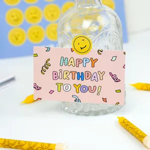Pink birthday greeting card with cute colorful typography and funny smiley face sticker.