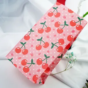 Detailed view of pink cherry print gift paper bag with cute polka dot hearts design for parties.