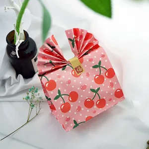 Detailed shot of pink cherry polka dot paper gift bag with cute folded top and sticker.