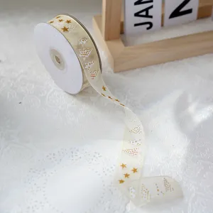 Christmas organza ribbon with gold stars and trees pattern for gift wrapping and decor.
