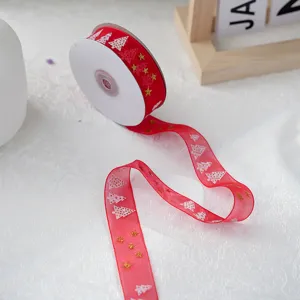 Close-up of red organza Christmas ribbon with gold stars and white trees for holiday gift wrapping.