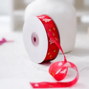 Detail shot of a red organza ribbon roll featuring gold stars and white Christmas trees.