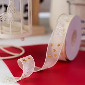Detail close-up of organza ribbon with gold stars and Christmas tree prints for gifts.